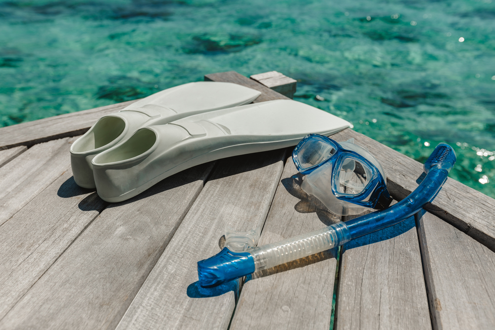 snorkeling gear on a pier with turquoise water in the background