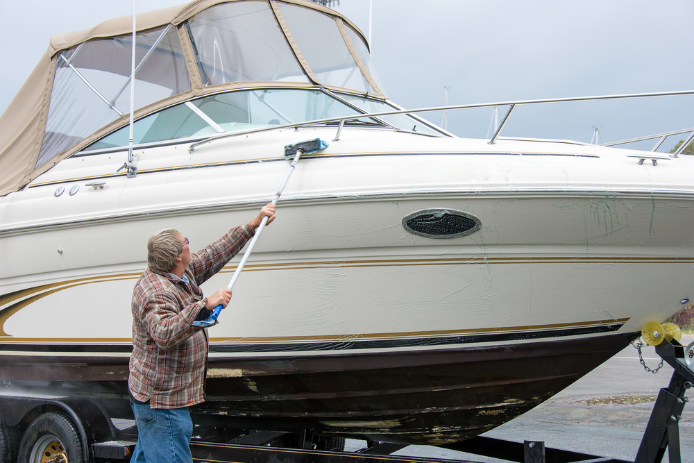 Person cleaning a boat with a long scrubber
