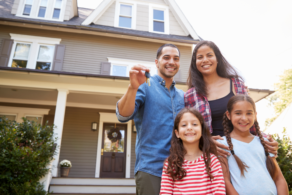 Hispanic family in front of house with the father holding keys to house