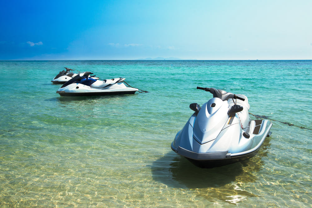 Two jet skis docked on a beach