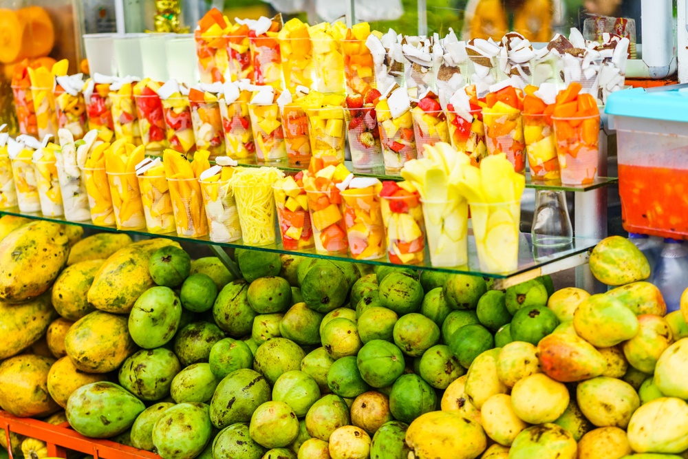 Fruit stand with various tropical fruits cut up into a cup